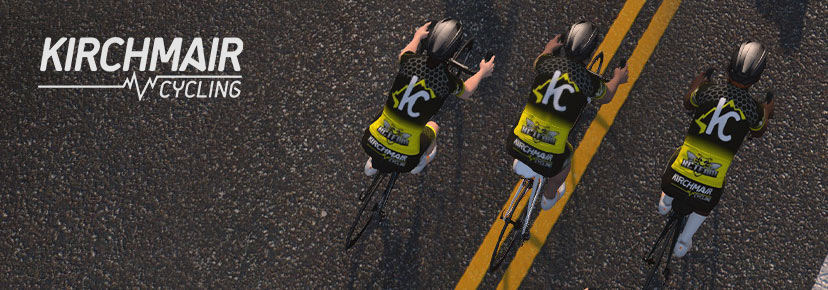 Three cyclists in black and yellow Kirchmair jerseys ride side by side on a road with double yellow lines; the Kirchmair Cycling logo appears on the left.