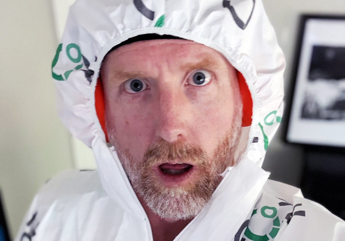 A man with a surprised expression wearing a white hooded suit, possibly designed for training or exercise, with a blurred background.