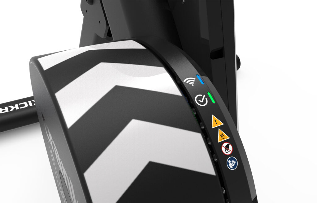 Close-up of a fitness equipment component with bold black and white chevron stripes, illuminated indicator lights, and warning icons on the side.
