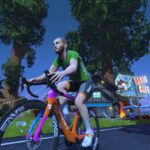 A person in a green shirt rides a colorful bicycle on a road at night, passing by a building with neon lights and surrounded by tall trees and flowers.