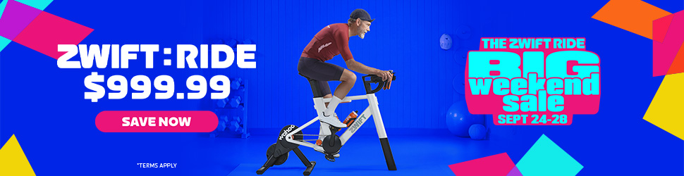 A man rides a stationary bike in a blue room. Text reads ZWIFT RIDE $999.99 and BIG weekend sale SEPT 7-28. Bright, colorful geometric shapes decorate the image.