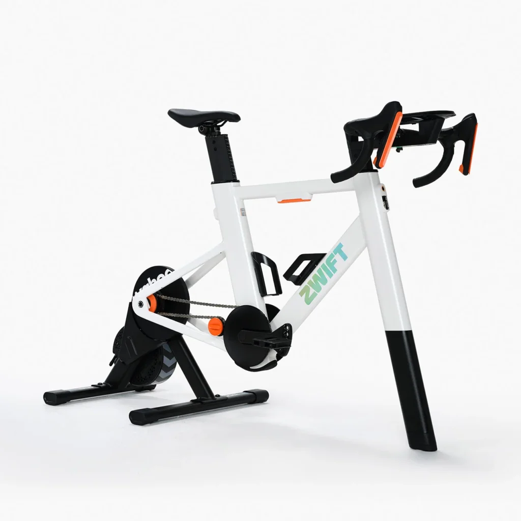 A stationary white indoor cycling bike with black and orange accents, the word ZWIFT on the frame, and a sturdy flywheel, set against a plain white background.