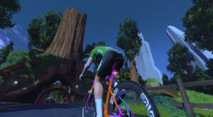 A cyclist in a green jersey rides an orange and pink road bike through a forest at night.