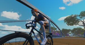 A cyclist wearing an orange cap and jersey rides a black road bike across a wooden bridge.