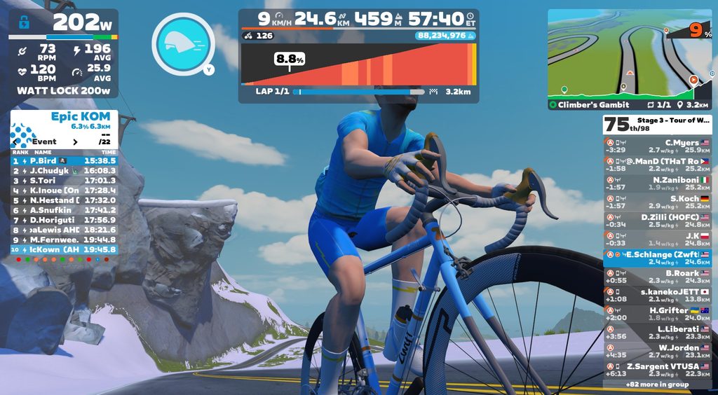 A first-person view of a cyclist in a blue jersey riding a blue road bike in a virtual cycling game, with digital HUD overlays displaying performance metrics, a course map, and a race leaderboard.