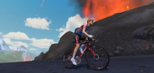 A cyclist in a polka-dot jersey rides a road bike along a volcanic landscape.