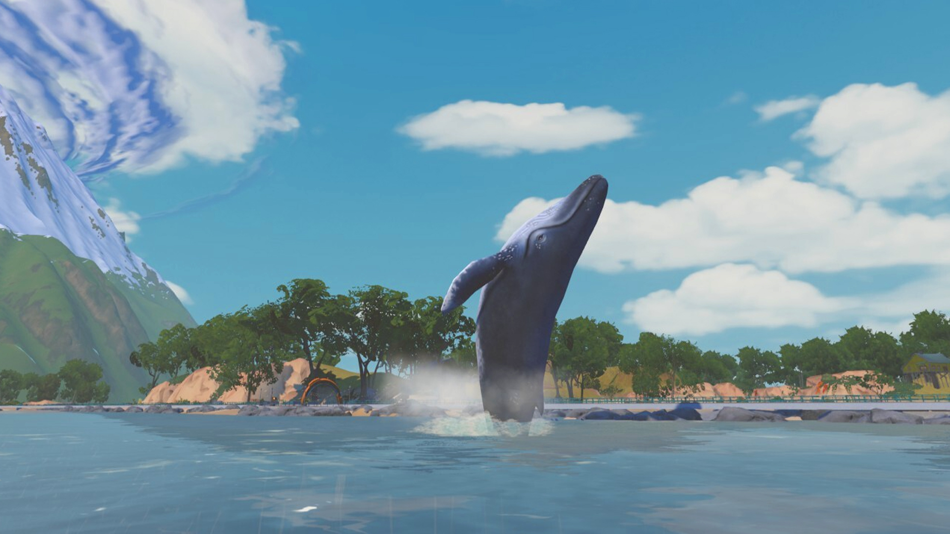 A whale breaches out of the water in front of a shore with trees and a snow-capped mountain.