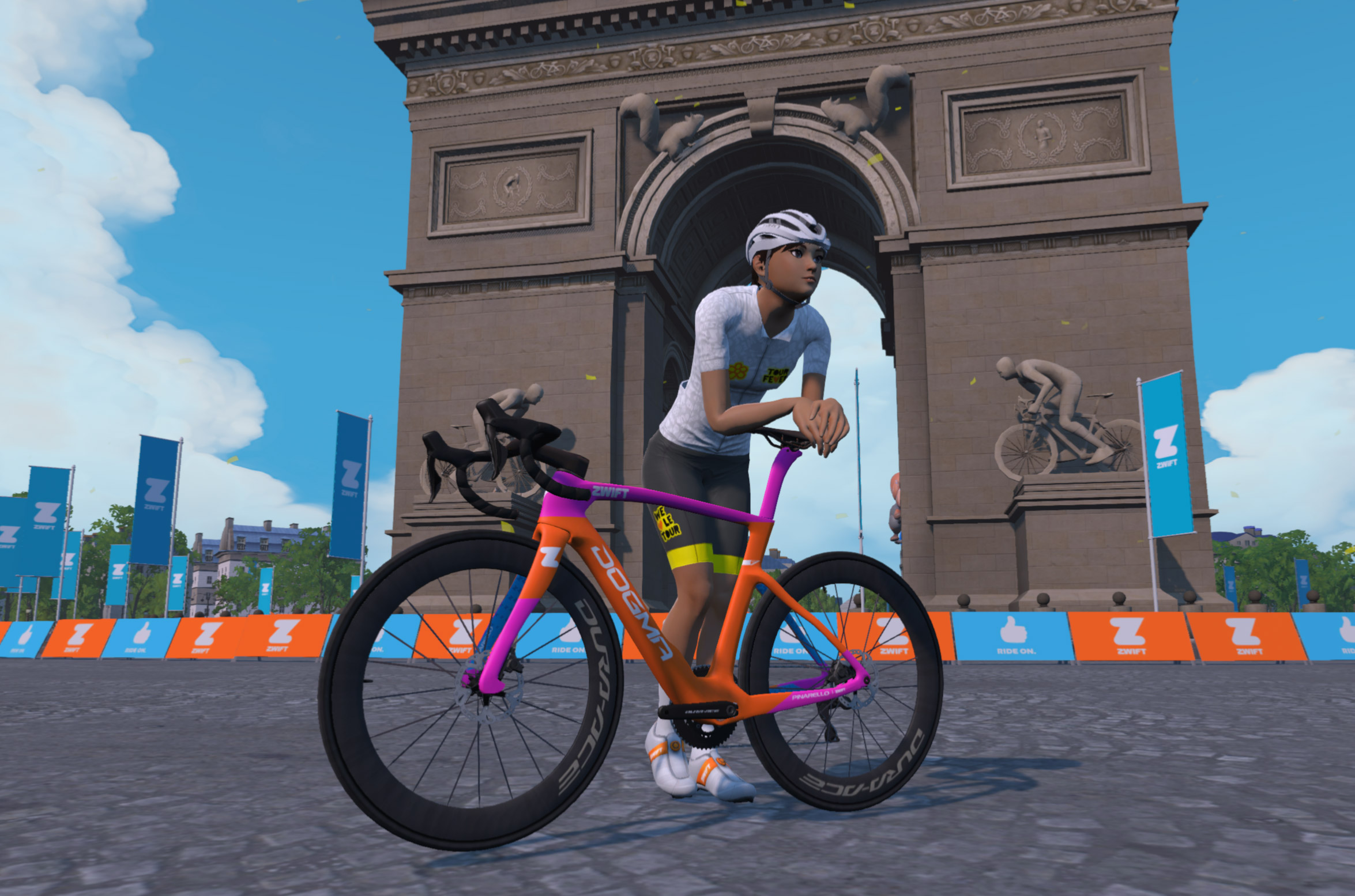 A cyclist in virtual gear leans on an orange and purple road bike in front of the Arc de Triomphe in a Zwift simulation.